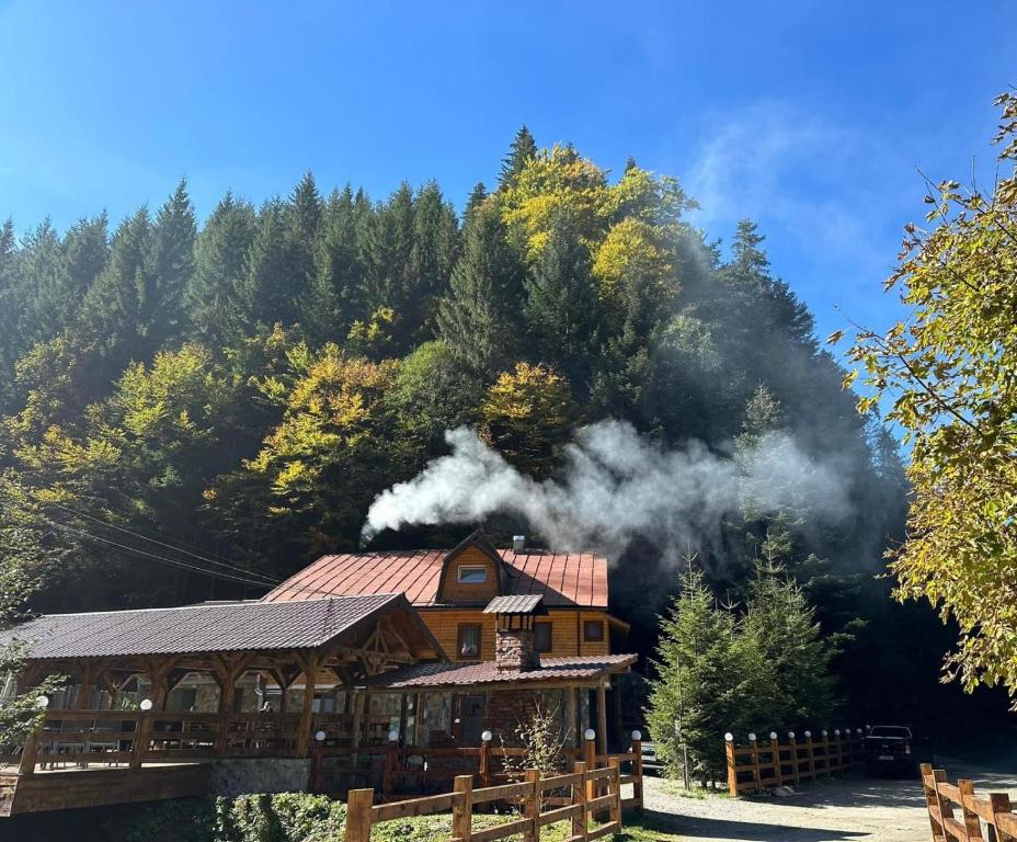 a log cabin with smoke coming out of it at CABANA MARIA-PETRIMANU in Ciungetu