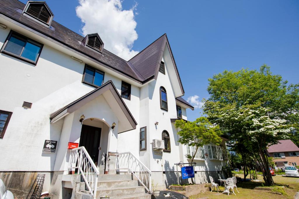a white house with a black roof at Pension Serenade in Hakuba