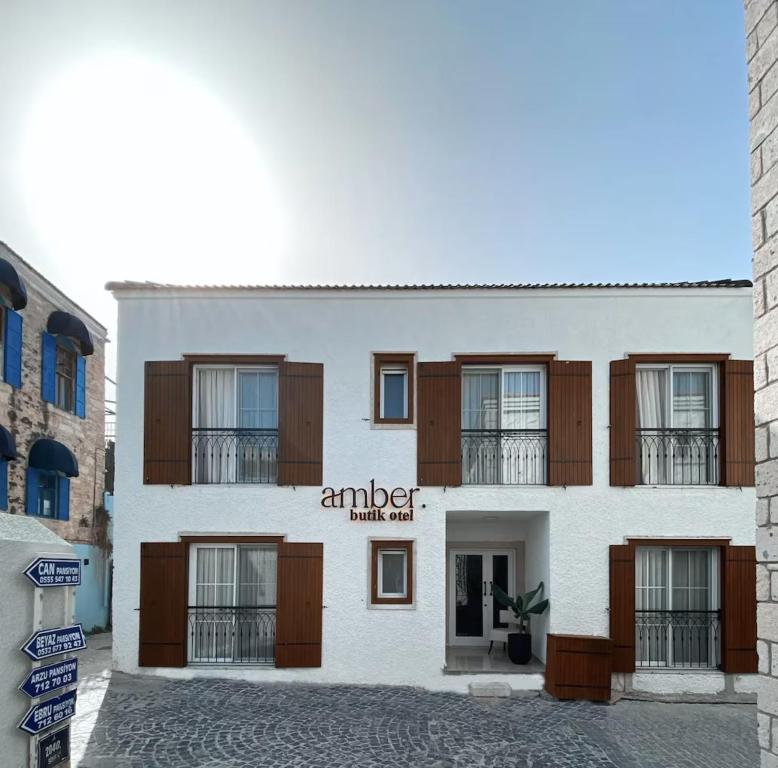 a large white building with wooden shuttered windows at Amber Butik Otel in Çeşme