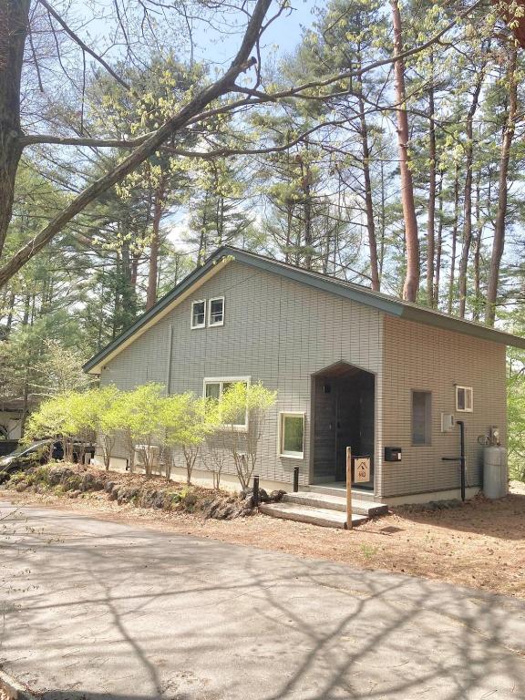 a gray house with a garage in the woods at Villa Mon Petit Nid Komoro in Komoro