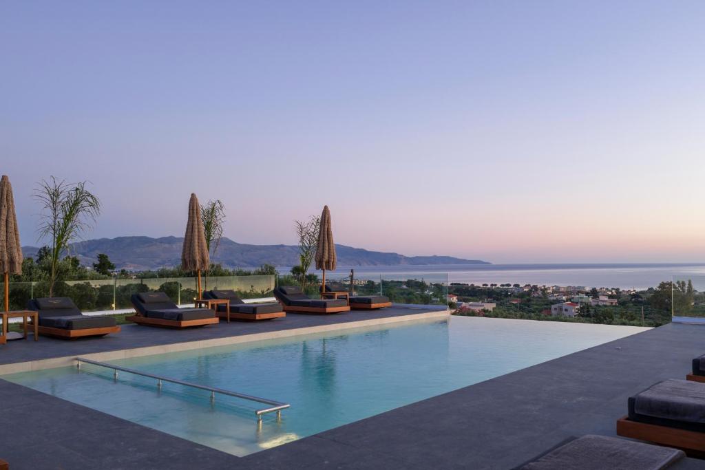a swimming pool with lounge chairs and the ocean at Infinite View Villa in Platanias