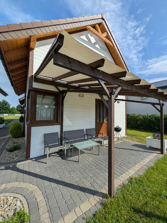 a pavilion with chairs and a bench on a patio at Białe Domki Mrzeżyno, wypoczynek w ciszy i zieleni in Mrzeżyno