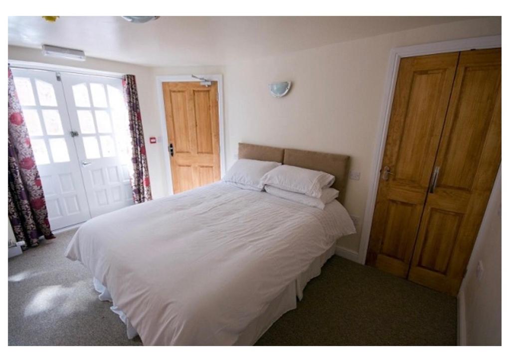 a bedroom with a bed with white sheets and a window at The Queens Head in Llanidloes