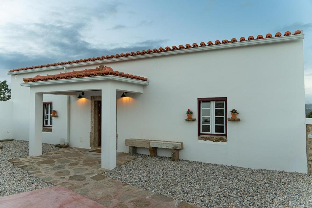 a white house with a bench in front of it at um pouco de campo in Torres Vedras
