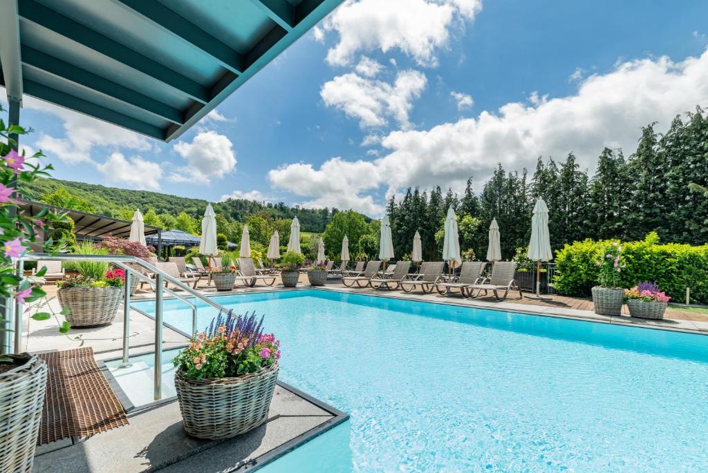 a pool at a resort with chairs and umbrellas at Göbels Schlosshotel "Prinz von Hessen" in Friedewald