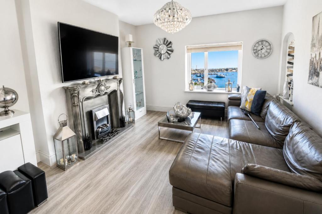 a living room with a leather couch and a television at Stunning Harbour View Beachfront Apartment Parking in Rhos-on-Sea