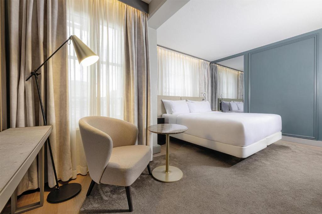 a hotel room with a bed and a chair at NH Collection Salzburg City in Salzburg