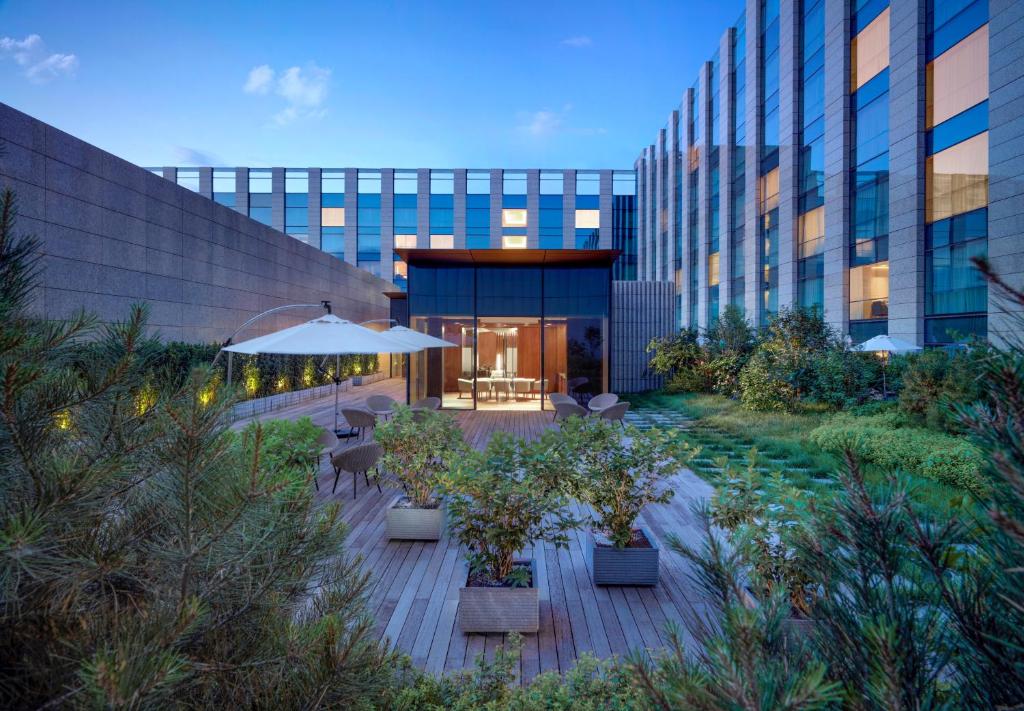a building with a patio with tables and an umbrella at Hyatt Regency Beijing Wangjing in Beijing