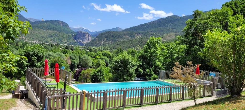 a swimming pool with a fence and mountains in the background at CAMPING PANORAMIQUE du VERDON in Castellane