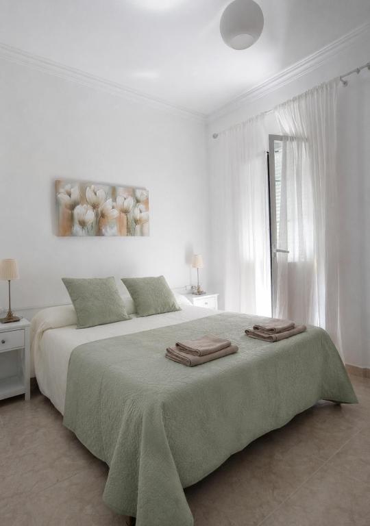 a white bedroom with a large bed with towels on it at Casa Paco & Carmela in Algodonales
