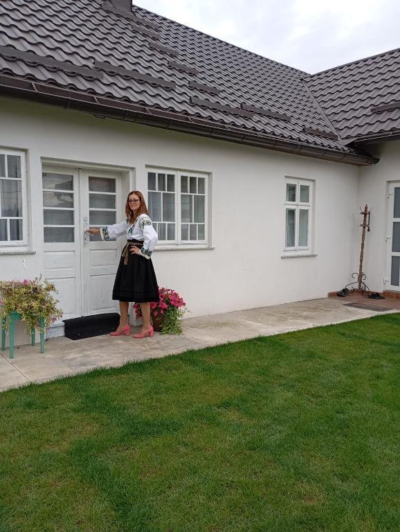 a woman standing in front of a house at Casuta bunicilor in Volovăţ