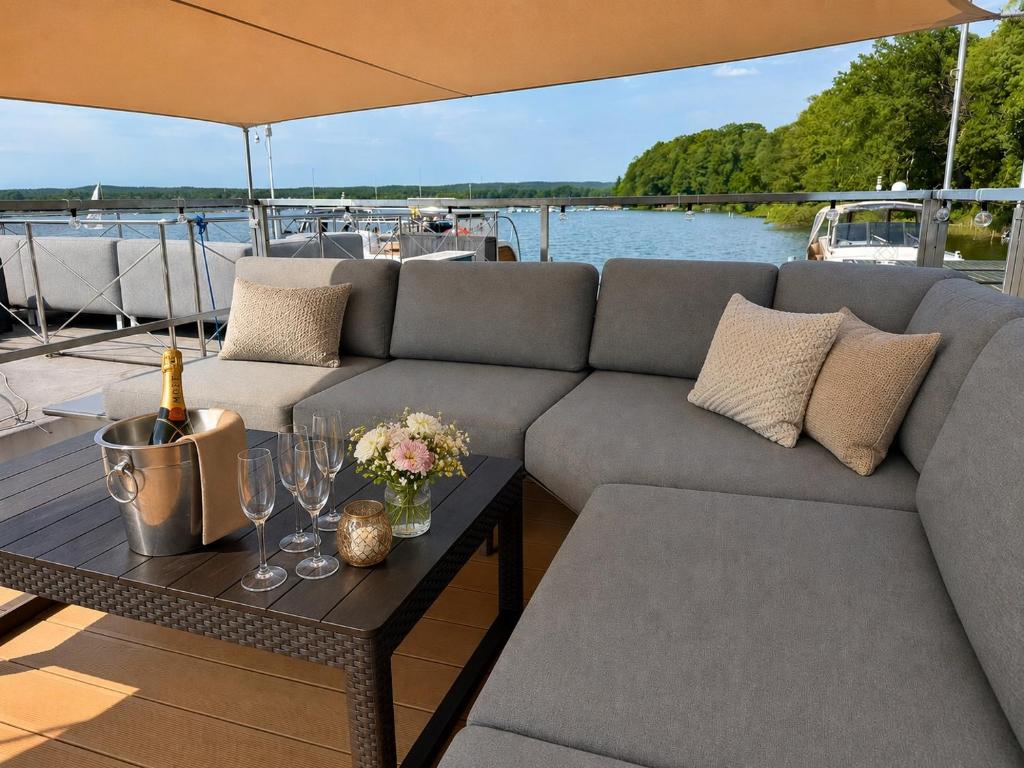 a couch and a table on a boat at Hausboot mit Sauna - TraumZeitBoot Heidi - exklusiver Festlieger in perfekter Lage am Scharmützelsee Bad Saarow in Bad Saarow