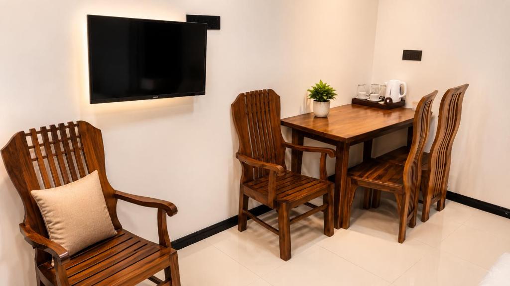 a room with a table and chairs and a television at Grand Stay Hotel in Seeduwa