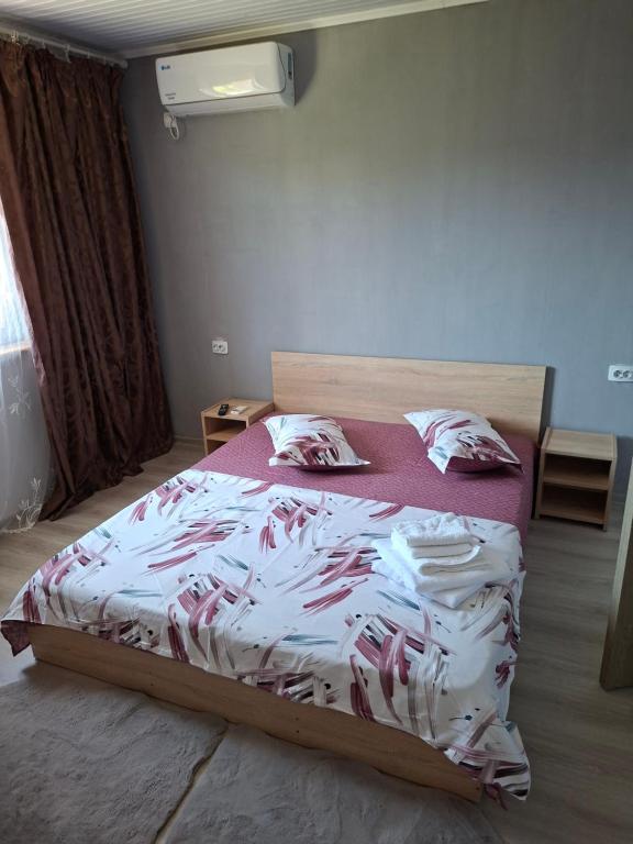 a bedroom with a large bed with a red and white comforter at Cozy House Corbu in Corbu