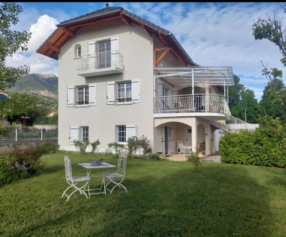 a house with a table and chairs in the yard at L'Ecrin Meublé de tourisme classé 3 étoiles climatisé in La Bâtie-Neuve