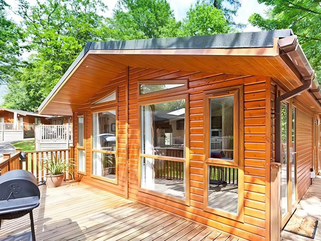 a wooden cabin with a deck and a grill at Beech Hill Lodge Beech Hill 9 at Fallbarrow Park in Windermere