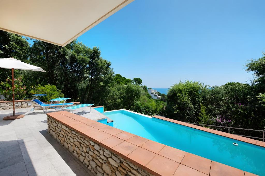 a blue swimming pool with tables and an umbrella at Villa Roberta Pool, wifi & Parking in Arenzano