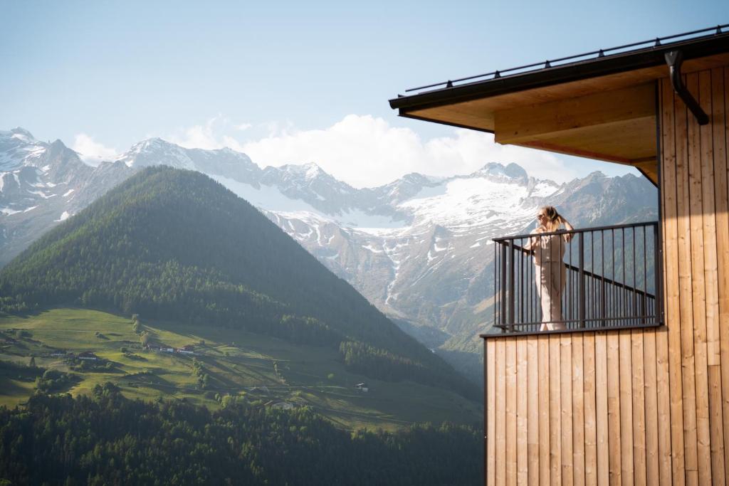 a woman standing on a balcony looking at the mountains at Lahnerhof Chalets - Mountain view and Sauna inclusive in Lutago