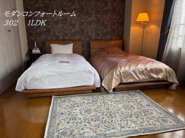 a bedroom with two beds and a rug on the floor at SakuraPiso in Kagoshima