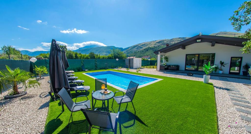 a backyard with a swimming pool and green grass at Holiday Home Nova Lux in Mostar