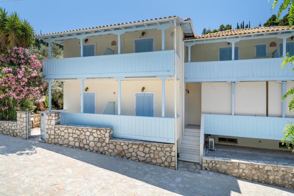 a white building with blue doors and a stone wall at Villa Milia 2 in Agios Nikitas