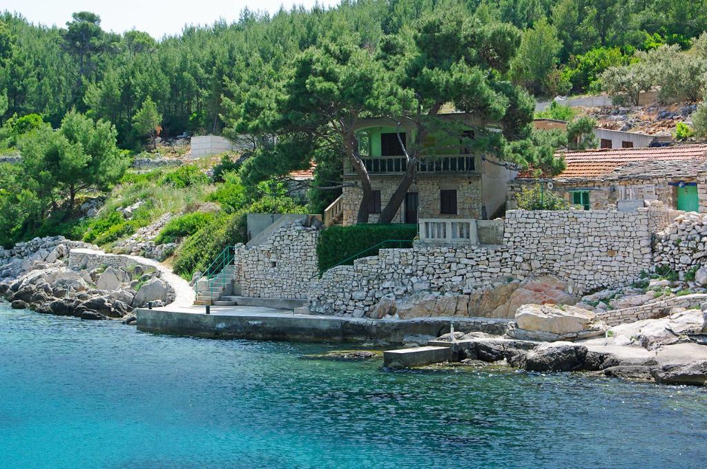 a house sitting on the side of a body of water at Apartments Olivera in Potirna