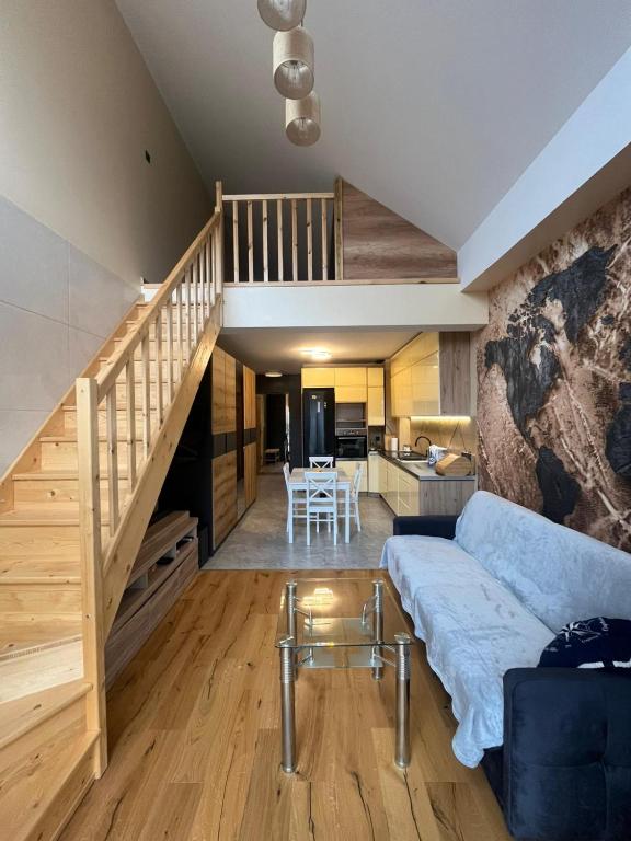 a living room with a blue couch and a staircase at Apartament Na Wspólnej in Łeba