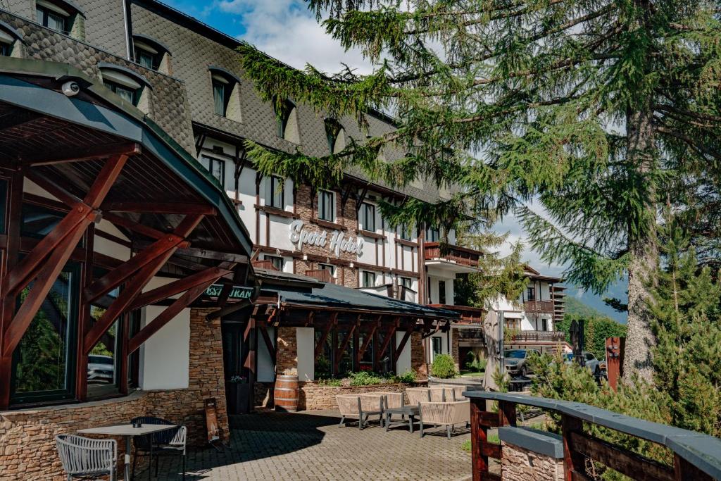 a hotel with tables and chairs in front of a building at Šport Hotel *** Donovaly in Donovaly
