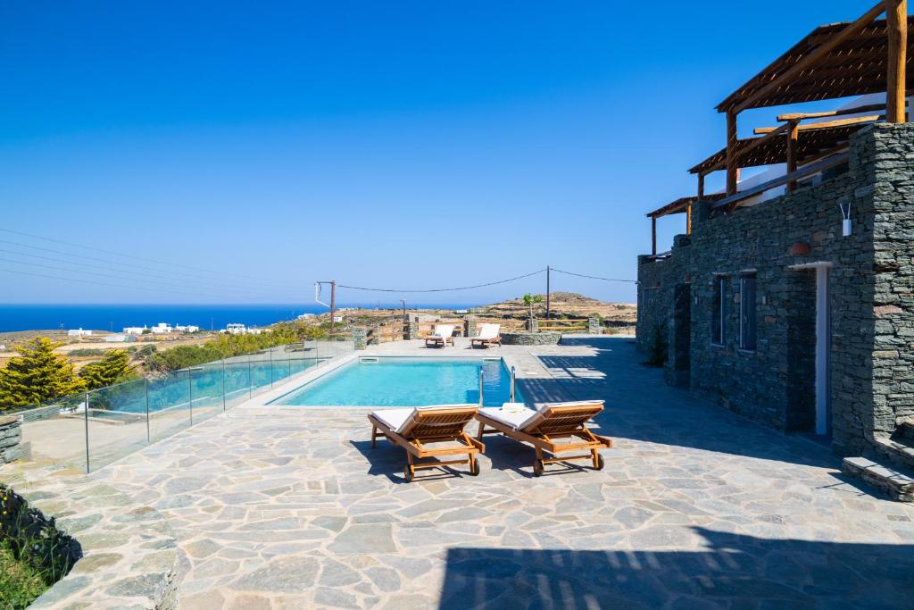 a villa with a swimming pool and two chairs at Taeri Sifnos in Sifnos