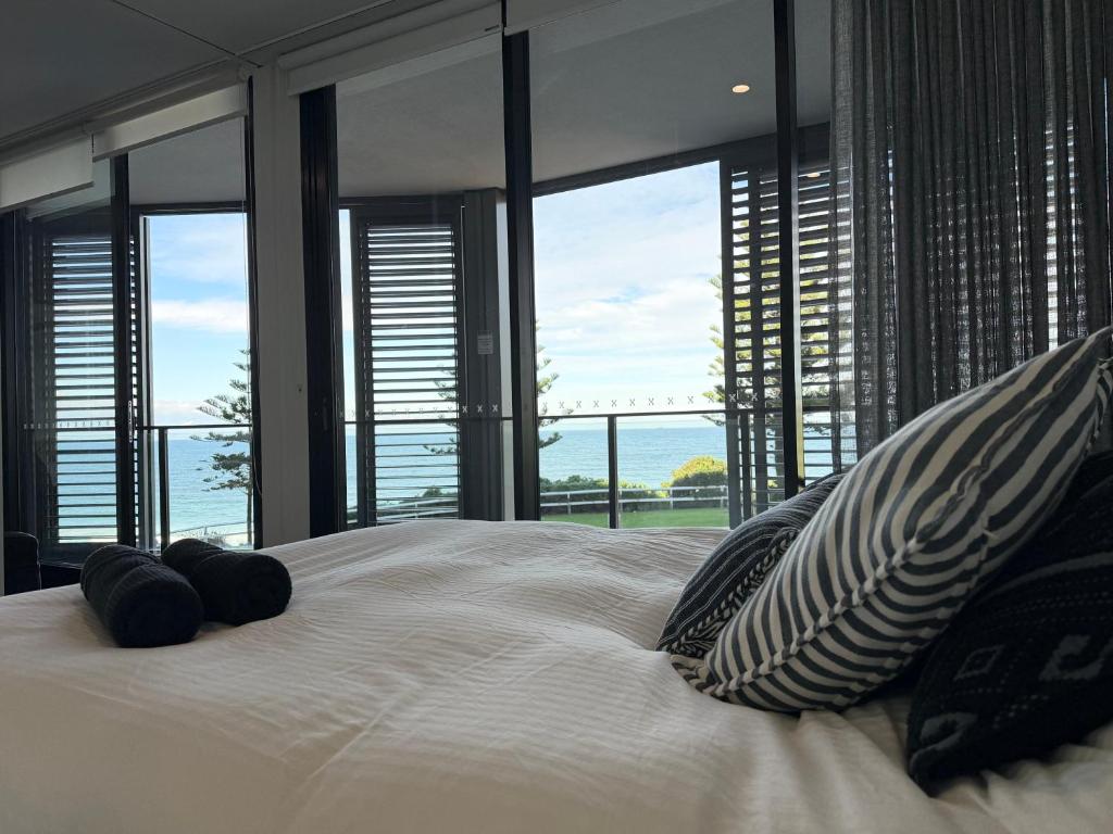 a bedroom with a large bed with large windows at Newcastle Beach Escape in Newcastle