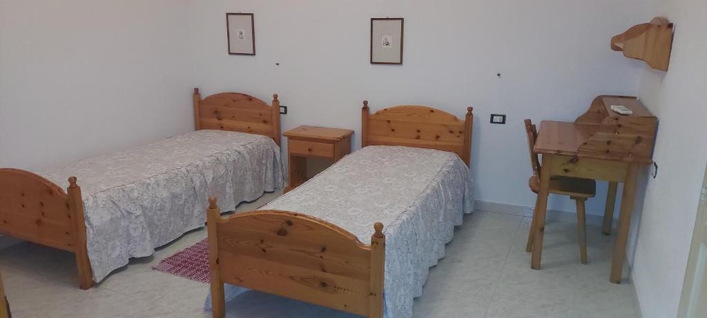a room with two beds and a table and a desk at Alloggio Ziu Oreddu in Orgosolo