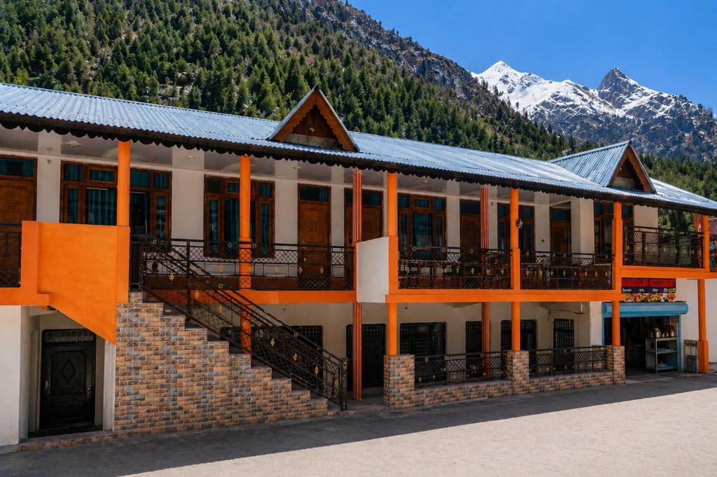 a building with mountains in the background at Hotel Chandra Lok Cottage Kabra Niketan in Gangotri