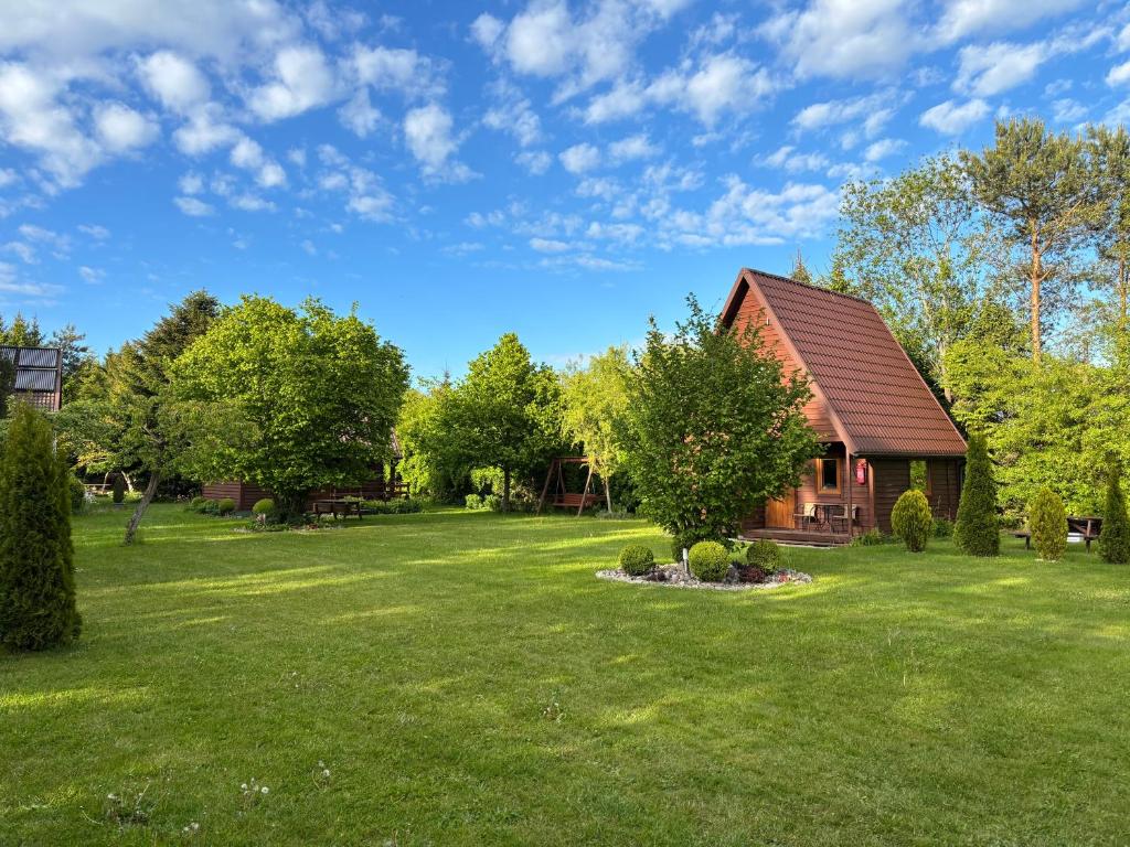 a house in a yard with a green lawn at Agroturystyka i Domki Zacisze in Jarosławiec