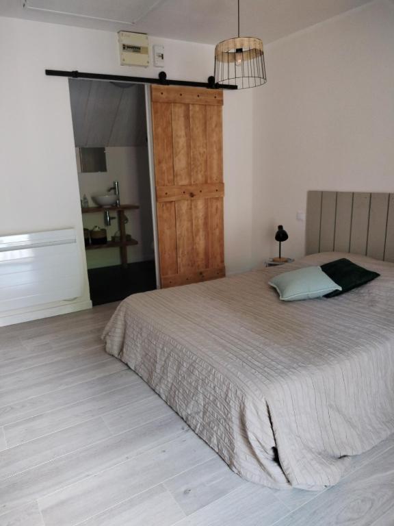 a bedroom with a bed and a wooden door at La maison d'André in Laurière
