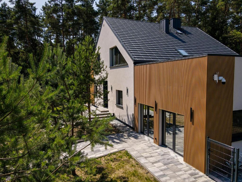 a house with a black roof at Willa na wyłączność z jacuzzi - Willa Natura Anastazewo in Szydłowiec