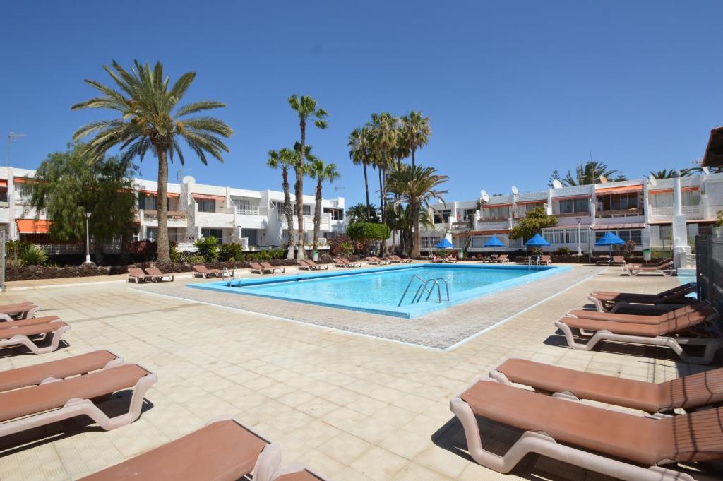 a swimming pool with lounge chairs and a resort at Pino's Vivienda Vacacional in Costa Del Silencio