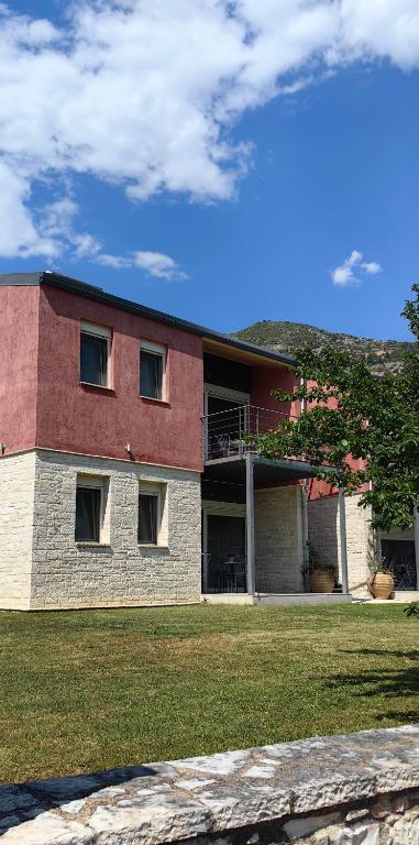 a red and white building with a grass yard at Zois Apartment in Gliki