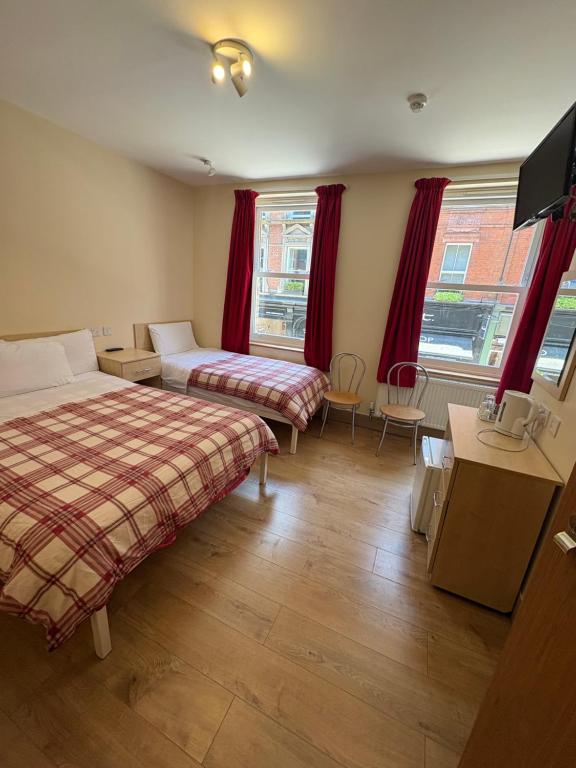 a hotel room with two beds and red curtains at Seven Dials Hotel in London
