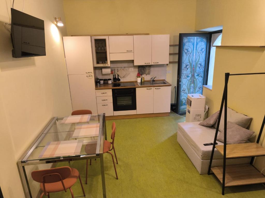 a living room with a glass table and a kitchen at Tra Vicoli e Natura in Piediluco