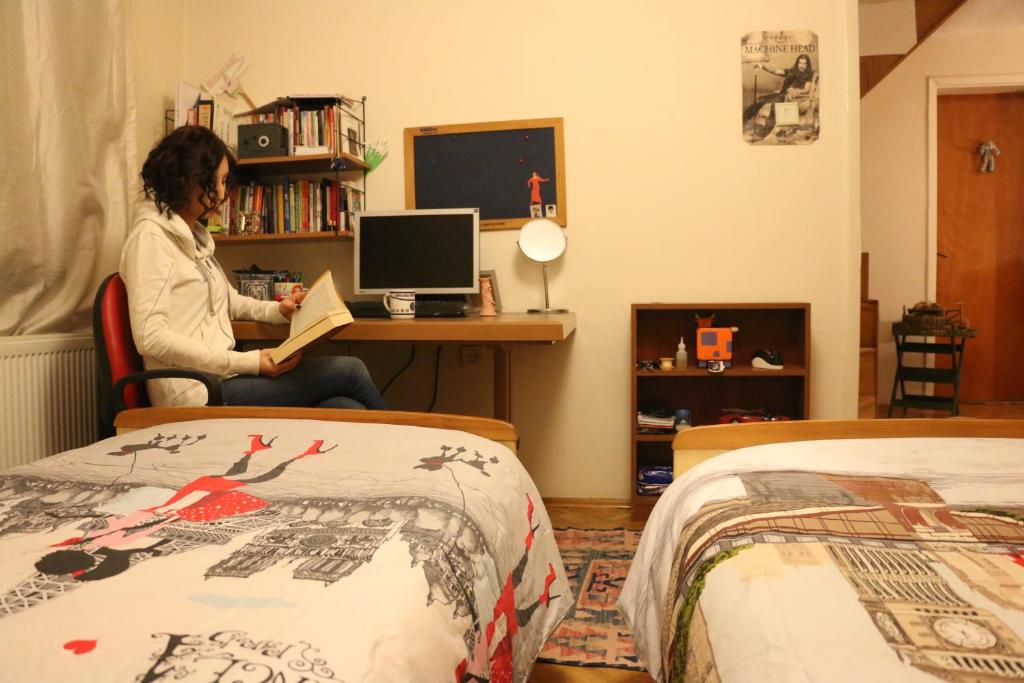 a woman sitting at a desk in a room with two beds at Best Room in Town in Karakusunlar Köyü