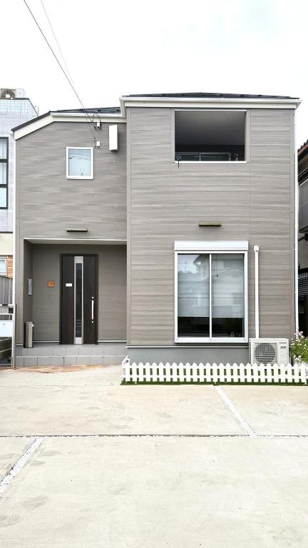 ein graues Haus mit einem Fenster an der Seite in der Unterkunft The Maruko丸子 in Abiko