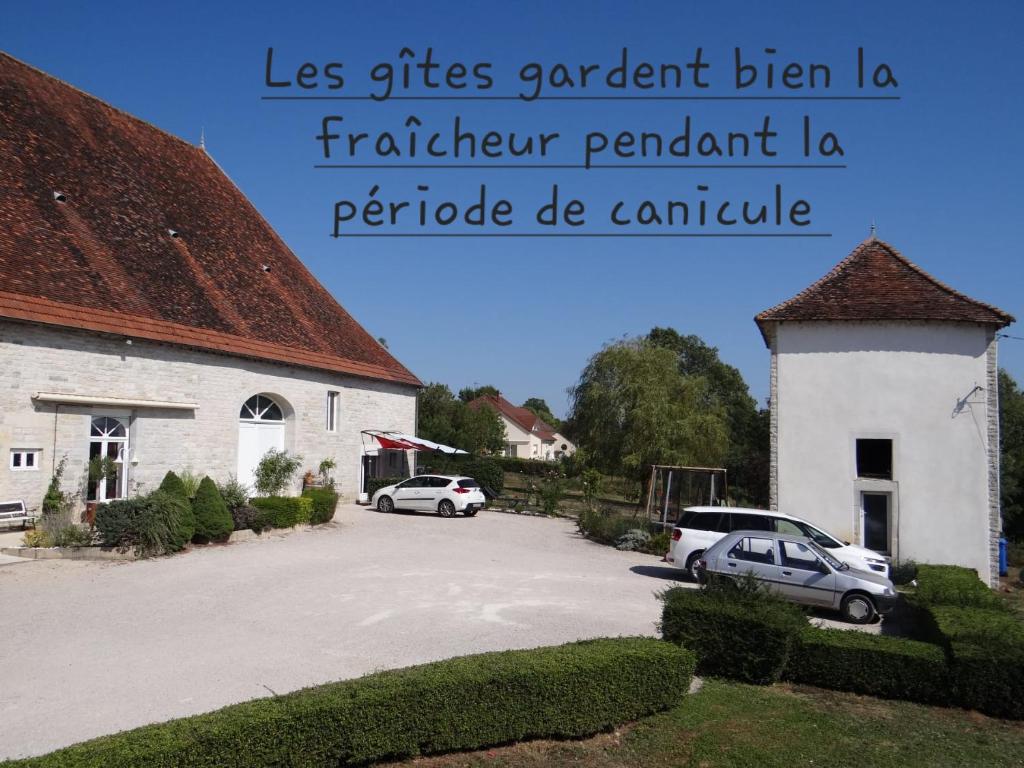 two cars parked in a parking lot next to a building at Gîte L'étable in Dole