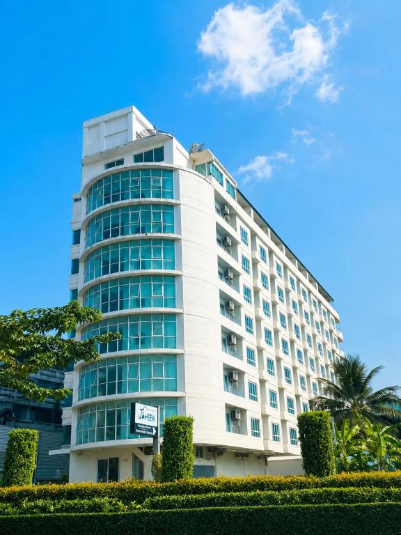 a tall white building with a palm tree in front of it at The View Residence in Bangkok