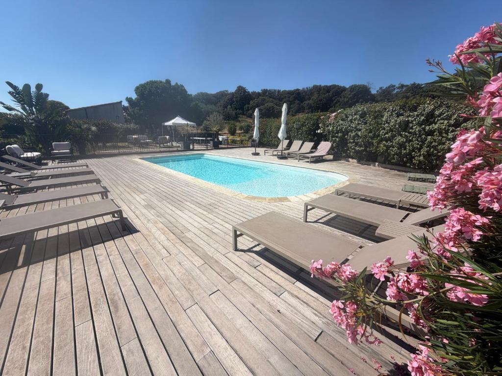 a swimming pool with chaises and chairs on a wooden deck at Les Bergeries d'Alata Hôtel de charme & suites avec piscine in Alata