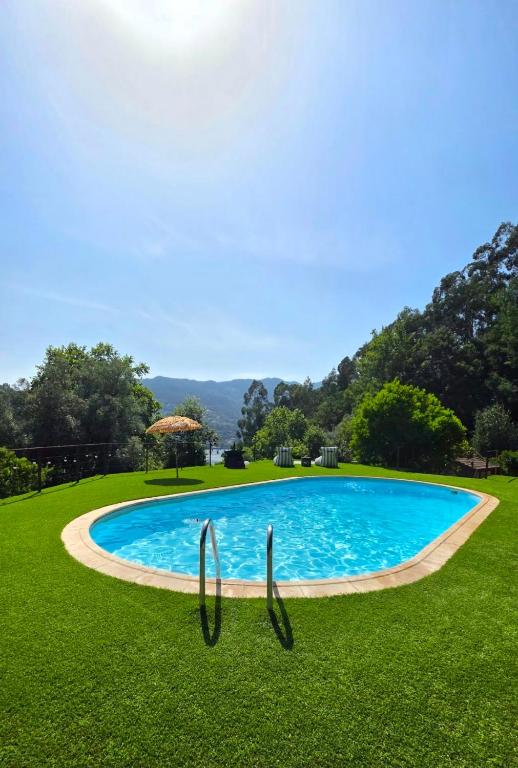 a swimming pool in the middle of a grass field at Ferreirinha Valley in Vieira do Minho