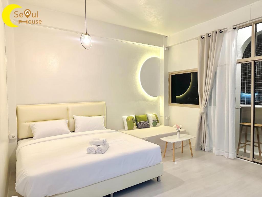a white bedroom with a bed and a table at Seoul House นครสวรรค์ in Sathani Pak Nam Pho
