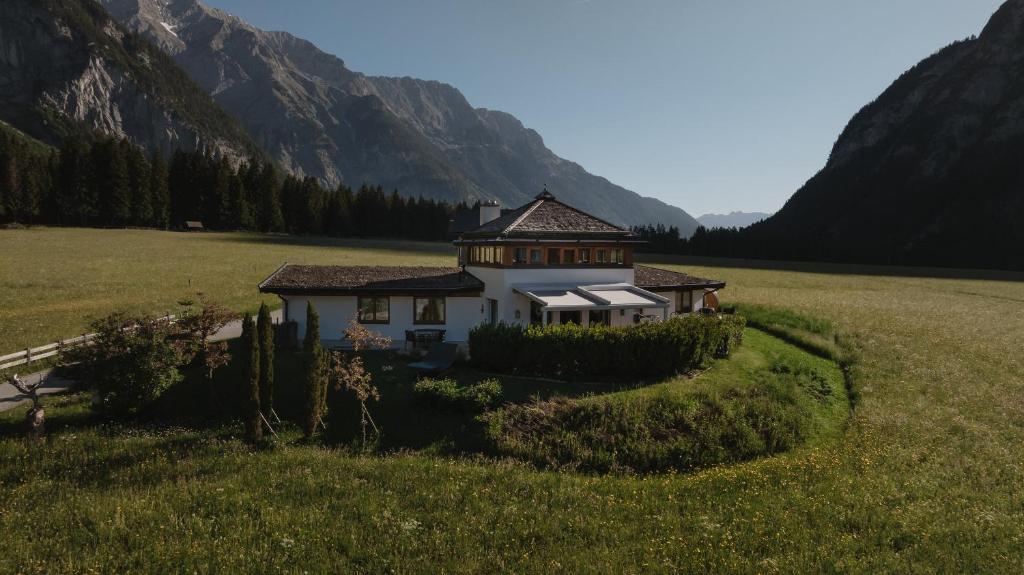 a house in a field with mountains in the background at Lehner Schlössl in Leutasch