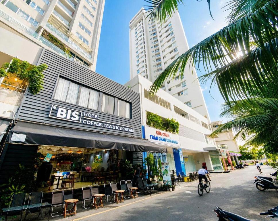 a person riding a bike down a street with buildings at Bis Hotel Hồ Chí Minh in Chợ Phước Hải