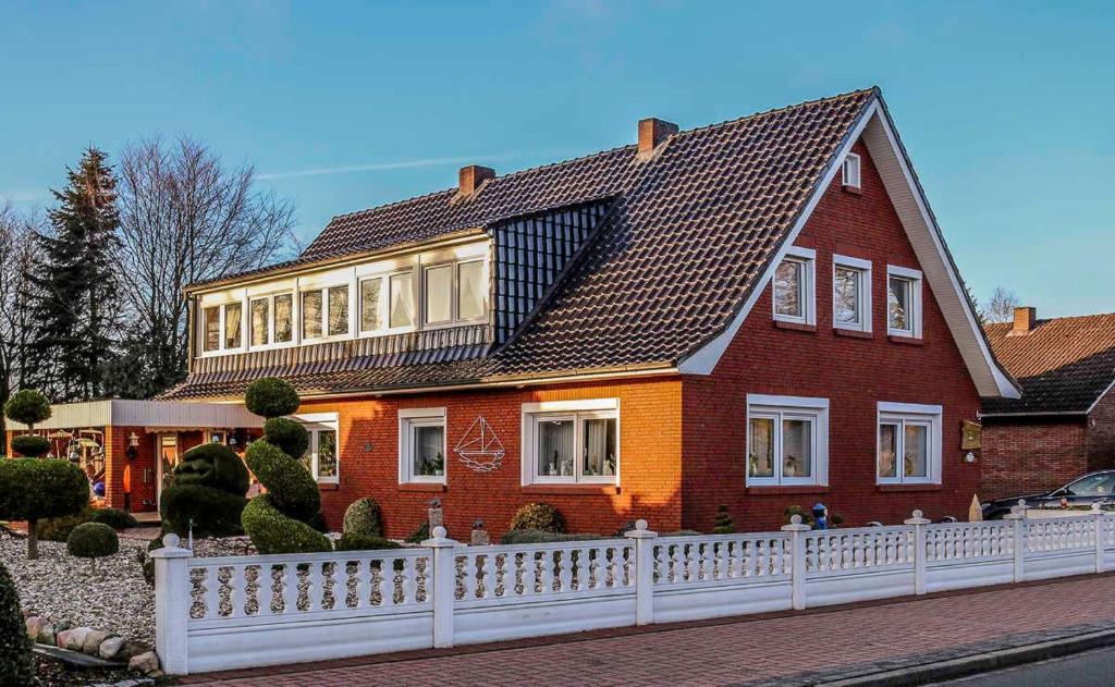 a large red house with a white fence at Ferienwohnung Schoon, 85042 in Ostrhauderfehn