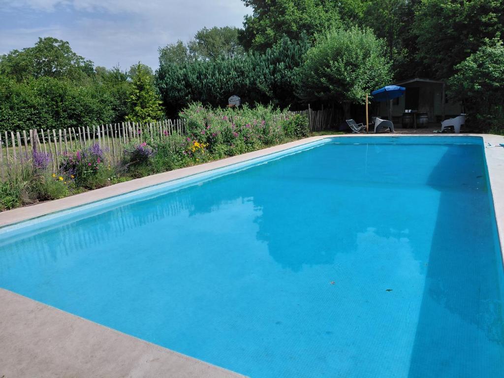 a large blue swimming pool in a yard at La Canardière in Pendé